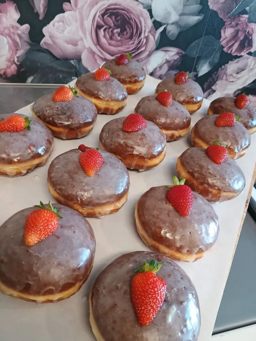 Lukrowane pączki z truskawkami na tle tapety w róże z naszego lokalu